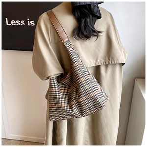 Detail of classic houndstooth tote bag with brown leather strap worn with beige coat