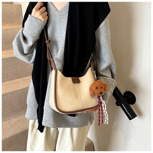 Beige and brown crossbody bag with poodle charm and FASHION label on model in natural light