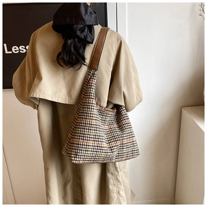 Checkered tote bag with leather strap shown on model wearing khaki trench coat