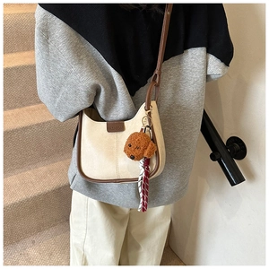 Detail of cream leather crescent bag featuring a contrast brown trim and fashion leather tag