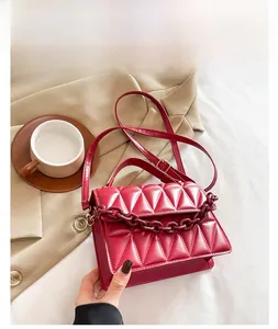 Détail du sac rouge en similicuir matelassé avec chaîne acrylique et bandoulière assortie