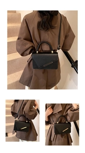 Detail view of black lychee grain leather handbag with gold metal clasp and shoulder strap
