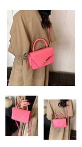 Detail of pink lychee leather handbag with gold metal trim and top handle in studio