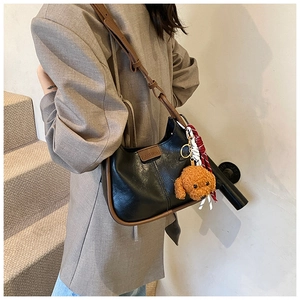 Close-up of minimalist black hobo bag with brown straps and cute puppy pendant