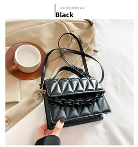 Détail du sac bandoulière noir matelassé avec chaîne épaisse et texture à losanges