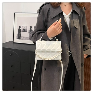 Gros plan d'un sac à bandoulière matelassé blanc avec chaîne épaisse et cuir PU mat