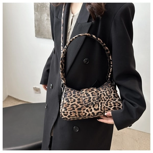Détail du sac léopard tendance avec boucle en métal et large bandoulière sur blazer noir