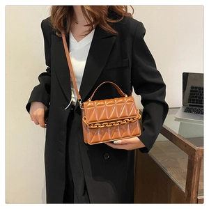 Détail d'un sac à bandoulière matelassé marron avec chaîne épaisse et bandoulière