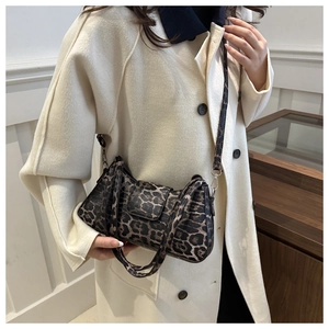 Trendy leopard print shoulder bag with gold buckle and adjustable strap on a female model