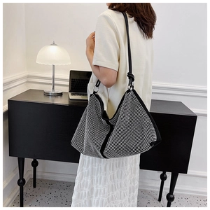 Detail of rhinestone shoulder bag with large capacity and knotted strap on white dress