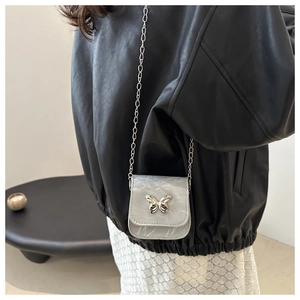Mini crossbody bag with marble texture and silver butterfly buckle on a model outfit