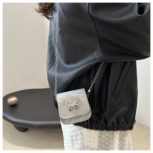 Detailed side view of mini crossbody bag with butterfly buckle and silver chain strap