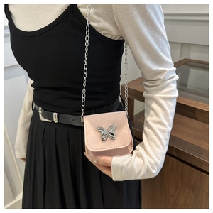 Detail view of mini pink crossbody bag with silver butterfly and delicate chain strap