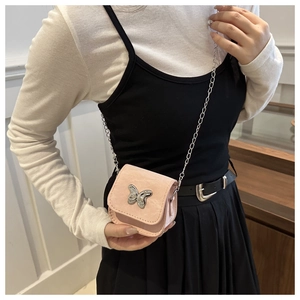 Detail of pink mini bag with silver butterfly hardware and metal chain strap worn by model