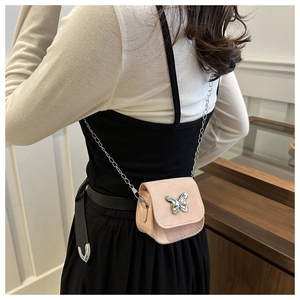 Close-up of pink mini crossbody bag with butterfly buckle and silver chain on model