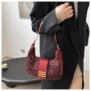 Gros plan du sac hobo léopard avec garniture en cuir rouge et boucle dorée sur modèle