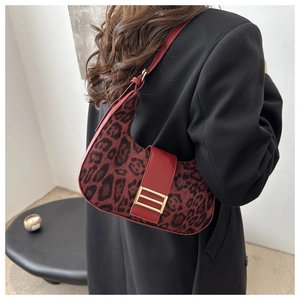 Détail du sac hobo léopard rouge avec boucle dorée porté à l'épaule par un mannequin