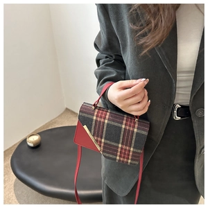 Detailed view of British style red plaid crossbody bag with gold metal hardware on model