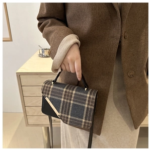 Detail of vintage plaid flap bag with gold hardware accent and black leather base
