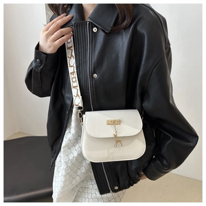 Detail of off-white saddle bag with golden deer pendant and geometric wide strap