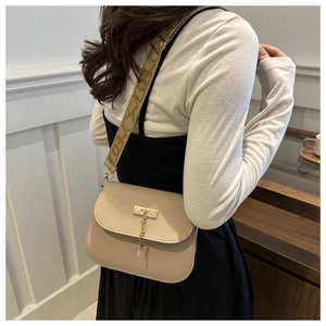 Detail of beige PU leather crossbody bag with golden deer charm and jacquard strap