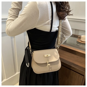 Detail of beige leather saddle bag with gold deer pendant and jacquard strap