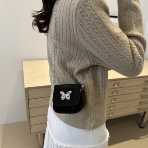 Mini black crossbody bag with silver butterfly and chain strap shown on a model
