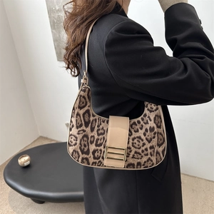 Borsa hobo leopardata con tracolla beige e fibbia dorata in un ambiente minimalista