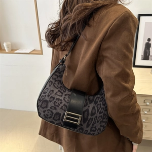 Borsa hobo chic con stampa leopardata e fibbia dorata portata a spalla da una donna in blazer
