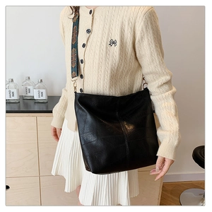 Detail of black faux leather tote with vintage patterned wide shoulder strap and metal buckle