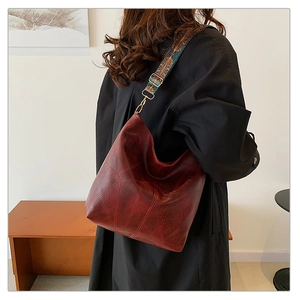 Detail of burgundy leather tote bag featuring a colorful ethnic style wide shoulder strap