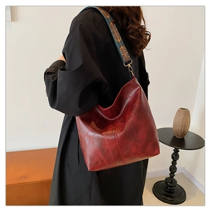 Detail of burgundy large shoulder bag with ethnic embroidered strap on model