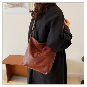 Detail of dark brown leather hobo bag with vintage texture and woven patterned strap