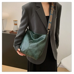 Detail of dark green textured leather tote bag with a colorful bohemian wide strap