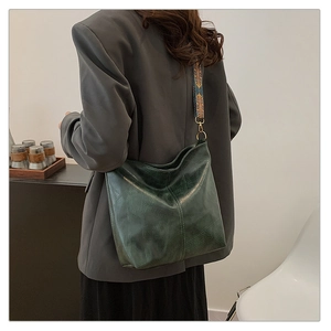Detail of dark green hobo bag with ethnic style jacquard strap and geometric texture