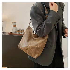 Detailed side view of vintage brown leather tote with folk-style geometric strap