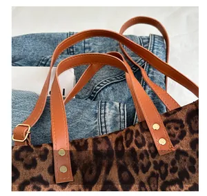 Close-up of leopard print tote bag featuring faux leather handles and gold rivet details