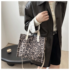 Detail of leopard print tote bag with canvas straps and gold rivets shown on model