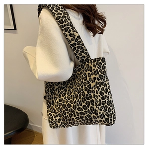 Close-up of leopard print canvas tote bag featuring a wide shoulder strap on a white coat