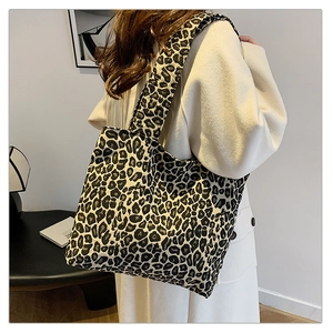 Close-up of leopard print canvas tote bag with wide shoulder strap on a model's shoulder