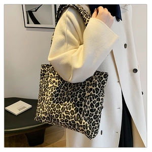 Detailed view of leopard print canvas tote bag styled with a minimalist cream coat