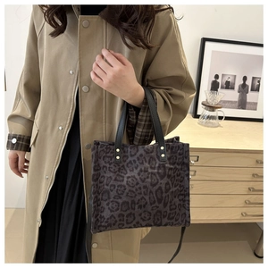 Detail of leopard print tote bag with plush texture and black leather handles