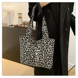 Detail of a large leopard print tote bag with wide shoulder straps in a stylish indoor setting