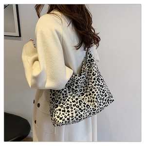Close-up of stylish black and white leopard print tote bag worn on shoulder by a model
