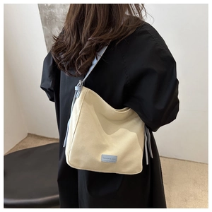 Détail du sac fourre-tout en toile crème avec bandoulières bleu clair et logo