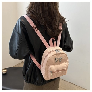 Pink mini backpack with silver metal bow detail shown on a leather jacket