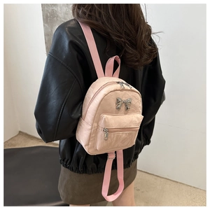 Detailed back view of a mini pink PU leather backpack with a silver metal bow accent