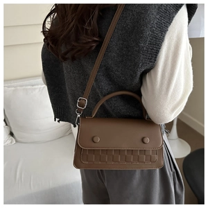 Detail of coffee brown crossbody bag with checkered texture and circular buckles