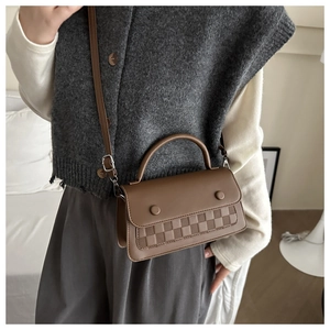 Detail of a brown crossbody bag featuring woven texture and silver-tone hardware accents