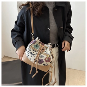 Detail of ethnic floral jacquard bucket bag with brown PU leather trim and gold zippers